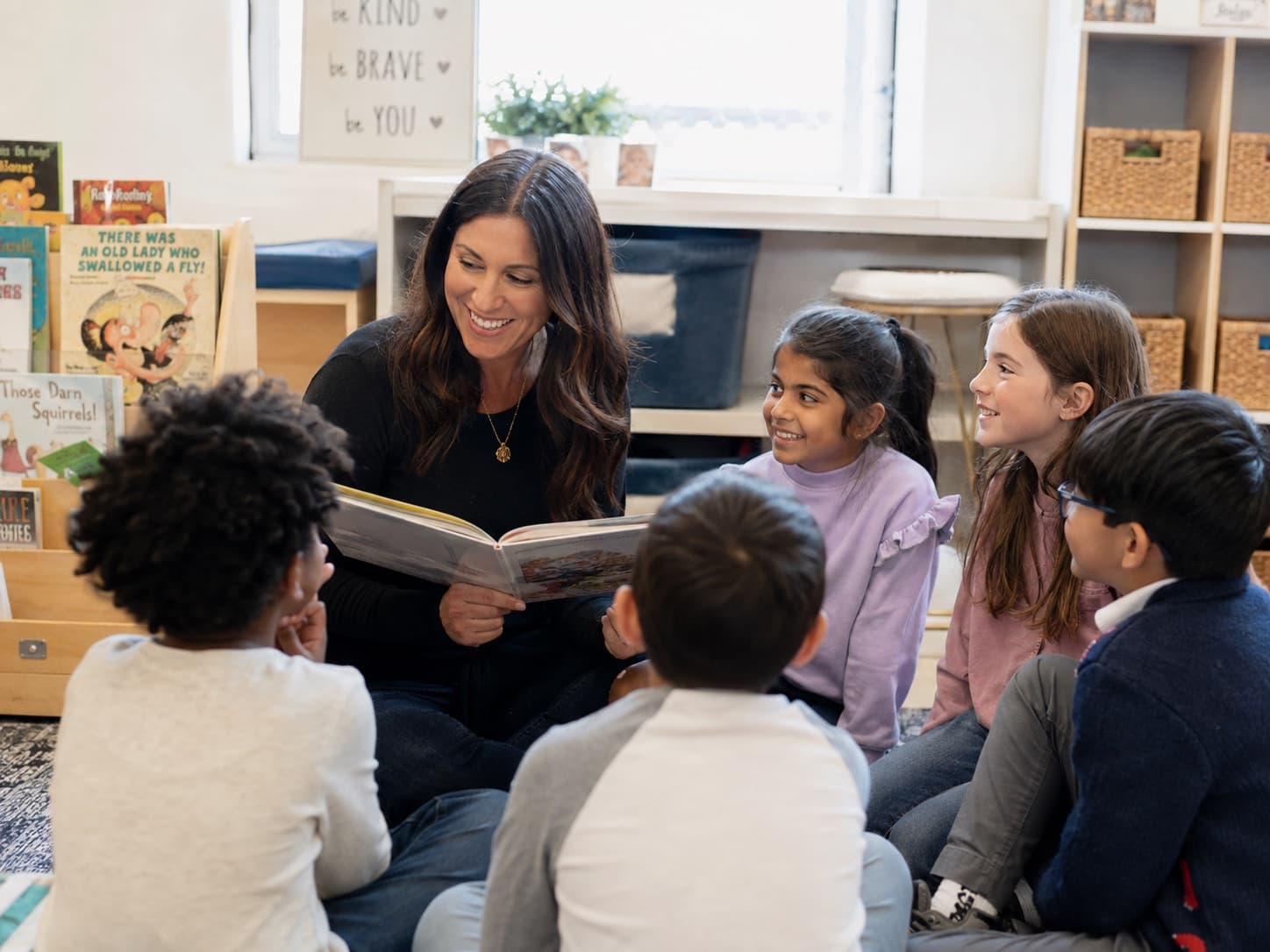 An elementary teacher reading with students in her classroom